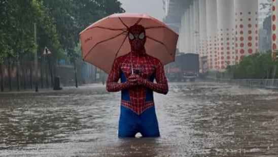 As Mumbai battles heavy rains, a man dressed as Spider-Man has gone viral, offering both laughs and a glimpse into the city's waterlogging struggles. Viral videos show the man wading through knee-deep water in Bhiwandi market, mop in hand, attempting to unclog drains and swim across waterlogged streets, much to the amusement of passersby and the internet alike.