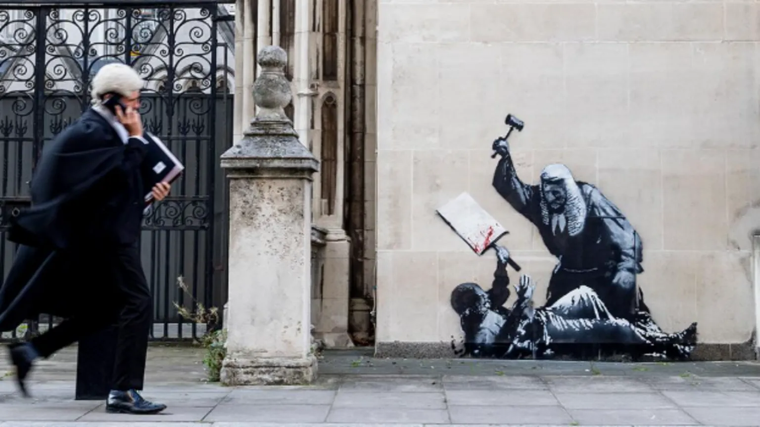 A new mural by elusive street artist Banksy has appeared on the side of the Royal Courts of Justice building in central London. It depicts a judge in a traditional wig and black robe hitting a protester lying on the ground, with blood splattering their placard.