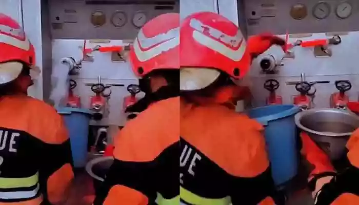 In the footage, a group of uniformed firefighters is seen using buckets from a nearby water source to pour over the flames. The video raises broader concerns