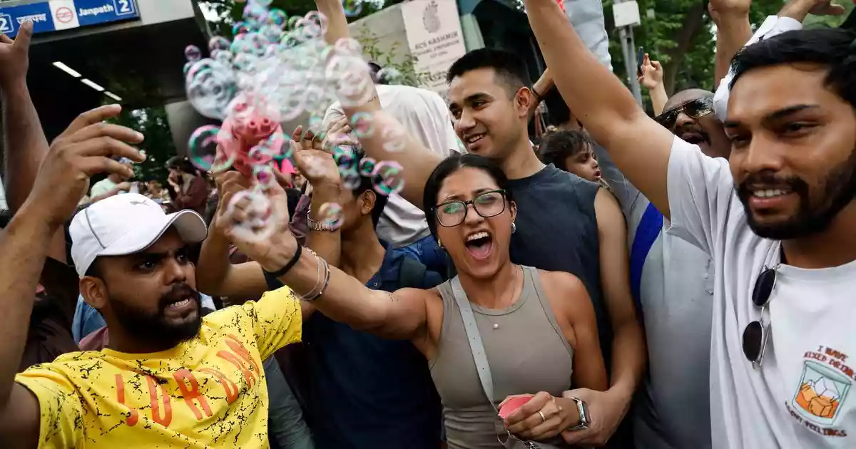 A young woman hoisted on the shoulders of her partner blowing bubbles in the air. A few hundred metres away, a crowd of very energetic men dancing to the beats