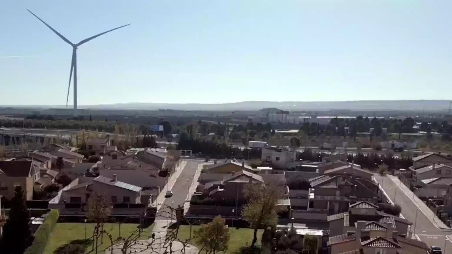 On the edge of the sleepy town of Figueruelas, a single, vast wind turbine spins around, casting its shadow over the buildings nearby