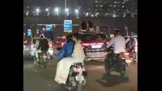 Women sit on sunroof of moving car